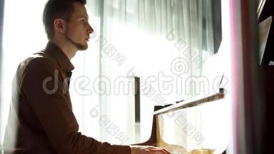 弹钢琴。 那个年轻人弹钢琴。 这位美丽的钢琴家演奏旋律。 室内窗户发出悦耳的灯光